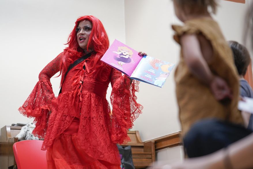 A drag queen who goes by the name Flame reads stories to children and their caretakers during a Drag Story Hour at a public library in New York, Friday, June 17, 2022. (AP Photo/Seth Wenig)