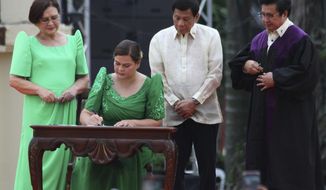 Sara Duterte, daughter of outgoing populist president of the Philippines, signs documents during her oath taking as vice president in her hometown in Davao city, southern Philippines, Sunday, June 19, 2022. Duterte clinched a landslide electoral victory despite her father&#39;s human rights record that saw thousands of drug suspects gunned down. Also in photo are, from left, her mother Elizabeth Zimmerman, Philippine President Rodrigo Duterte and Supreme Court Justice Ramon Paul Hernando. (AP Photo/Manman Dejeto)