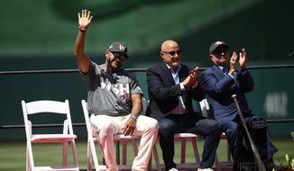 Washington Nationals manager Dave Martinez waves at a jersey retirement ceremony for former Washington Nationals baseball player Ryan Zimmerman before a baseball game between the Nationals and the Philadelphia Phillies, Saturday, June 18, 2022, in Washington. Also seen are general manager Mike Rizzo, center, and mark Lerner, right, principal owner. (AP Photo/Nick Wass)