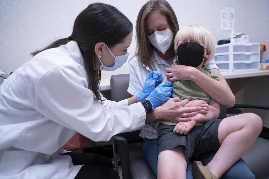 Pharmacist Kaitlin Harring, left, administers a Moderna COVID-19 vaccination to three year-old Fletcher Pack, while he sits on the lap of his mother, McKenzie Pack, at Walgreens pharmacy Monday, June 20, 2022, in Lexington, S.C. Today marked the first day COVID-19 vaccinations were made available to children under 5 in the United States. (AP Photo/Sean Rayford)