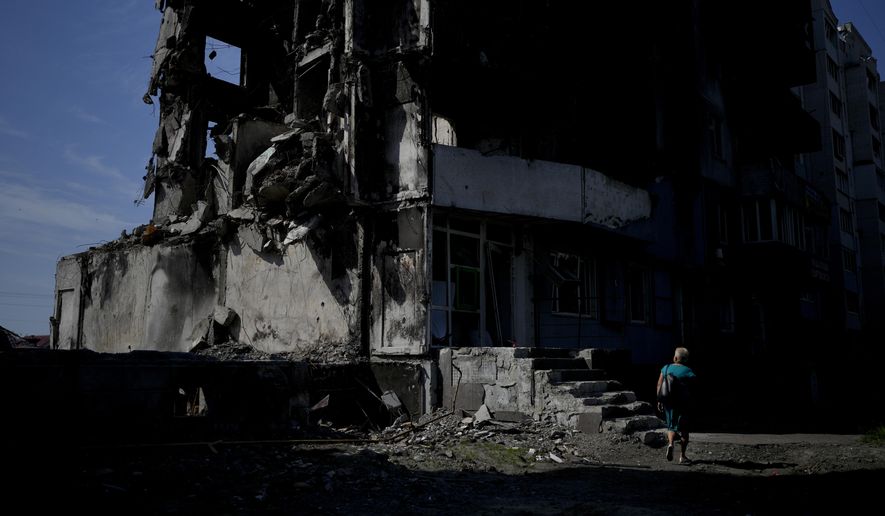 A woman walks past a building destroyed in Russian shelling in Borodyanka, on the outskirts of Kyiv, Ukraine, Tuesday, June 21, 2022. (AP Photo/Natacha Pisarenko)