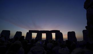 Dawn breaks behind the stones during the Summer Solstice festivities at Stonehenge in Wiltshire, England, Tuesday, June 21, 2022. After two years of closure due to the COVID-19 pandemic, Stonehenge reopened Monday for the Summer Solstice celebrations. (Andrew Matthews/PA via AP)