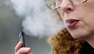A woman exhales while vaping from a Juul pen e-cigarette in Vancouver, Wash., April 16, 2019.  Federal health officials on Thursday, June 23, 2022 ordered Juul to pull its electronic cigarettes from the U.S. market, the latest blow to the embattled company widely blamed for sparking a national surge in teen vaping. (AP Photo/Craig Mitchelldyer) **FILE**