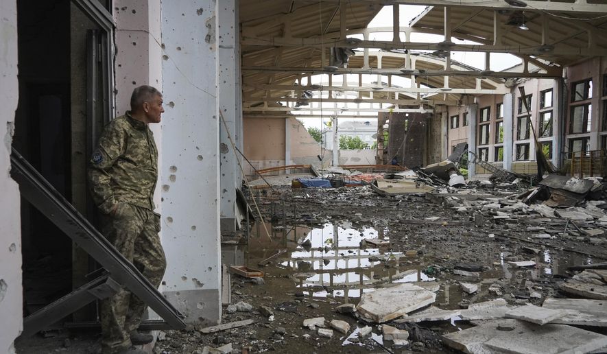 A Ukrainian serviceman looks at the ruins of the sports complex of the National Technical University in Kharkiv, Ukraine, Friday, June 24, 2022, damaged during a night shelling. The building received significant damage. A fire broke out in one part but firefighters managed to put it out. (AP Photo/Andrii Marienko)