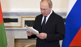 Russian President Vladimir Putin reads a paper as he waits Belarusian President Alexander Lukashenko for the talk in St. Petersburg, Russia, Saturday, June 25, 2022. (Maxim Blinov, Sputnik, Kremlin Pool Photo via AP)