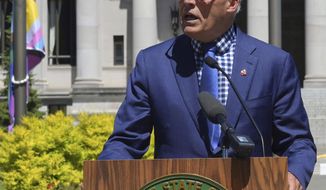 Washington state Gov. Jay Inslee addresses a gathering before raising the LGBTQ Pride Celebration flag seen behind him during a noon ceremony at the Capitol Campus flag circle, Tuesday, June 21, 2022, in Olympia, Wash. A variety of events celebrating the LGBTQ community statewide have taken place and are also scheduled through the month of June. (Steve Bloom/The Olympian via AP)