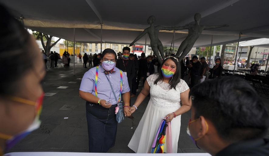 Dayanny Marcelo and her wife Mayela Villalobos react after a judge declare officially married during a mass wedding ceremony organized by city authorities as part of the LGBT pride month celebrations, in Mexico City, Friday, June 24, 2022. (AP Photo/Fernando Llano)