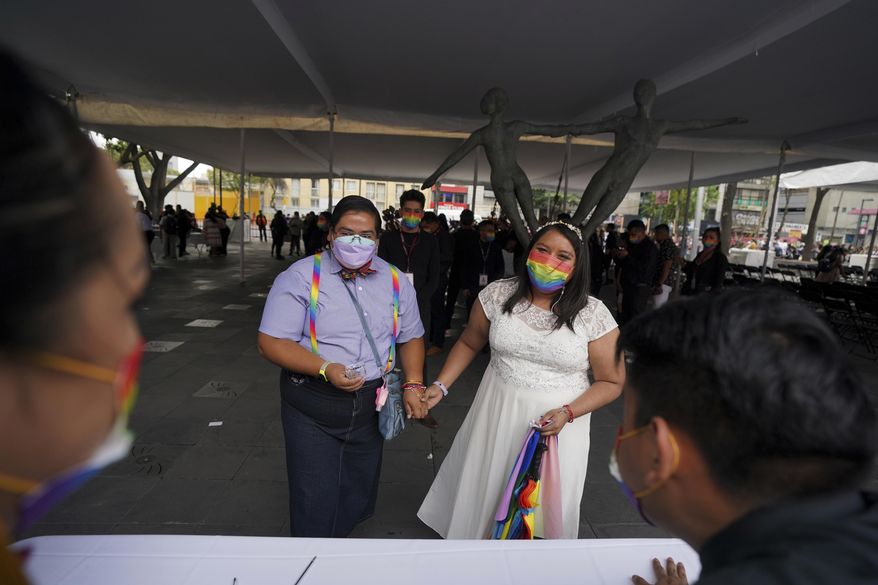Dayanny Marcelo and her wife Mayela Villalobos react after a judge declare officially married during a mass wedding ceremony organized by city authorities as part of the LGBT pride month celebrations, in Mexico City, Friday, June 24, 2022. (AP Photo/Fernando Llano)