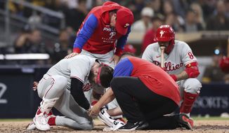 Philadelphia Phillies&#39; Bryce Harper, left, receives attention after being hit by a pitch while interim manager Rob Thomson, background left, and Nick Castellanos, background right, look on during the fourth inning of the team&#39;s baseball game against the San Diego Padres, Saturday, June 25, 2022, in San Diego. (AP Photo/Derrick Tuskan)