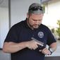 Kainoa Kaku, president of the Hawaii Rifle Association, checks one of his personal firearms as he discusses the recent U.S. Supreme Court Ruling while at his home, Thursday, June, 23, 2022, in Honolulu. (AP Photo/Marco Garcia)
