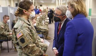 Ohio Gov. Mike DeWine, center, and his wife Fran, right, talk with specialist Emily Milosevic as they tour the Defense Supply Center Columbus in Columbus, Ohio, as members of the Ohio Army National Guard prepare to deploy to aid Ohio hospitals during the current surge in COVID-19 hospitalizations Jan. 6, 2022. Up to 40,000 Army National Guard soldiers across the country - or about 13% of the force — have not yet gotten the mandated COVID-19 vaccine, and as the deadline for shots looms, at least 14,000 of them have flatly refused and could be forced out of the service. (AP Photo/Paul Vernon, File)