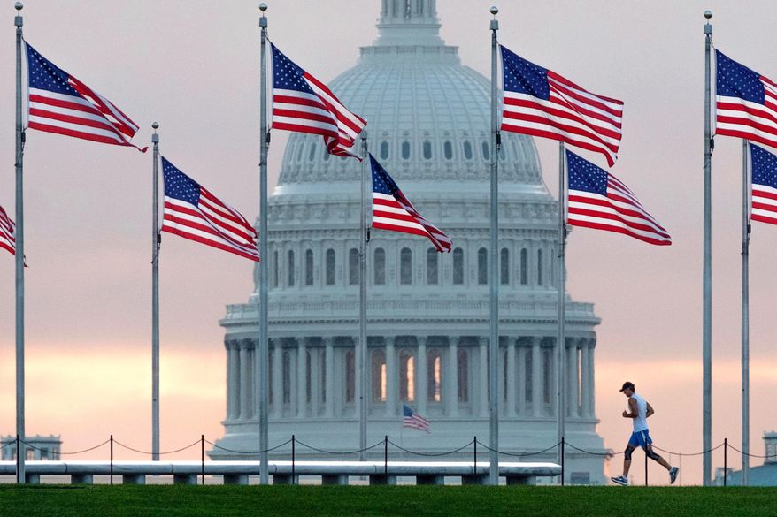 In this Sept. 27, 2017, file photo, an early morning runner crosses in front of the U.S. Capitol as he passes the flags circling the Washington Monument in Washington. (AP Photo/J. David Ake, File)