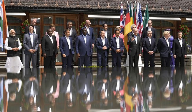U.S. President Joe Biden, front fourth right, waves as he poses with G7 leaders and Outreach guests for an official group photo at Castle Elmau in Kruen, near Garmisch-Partenkirchen, Germany, on Monday, June 27, 2022. The Group of Seven leading economic powers are meeting in Germany for their annual gathering Sunday through Tuesday. (AP Photo/Markus Schreiber)