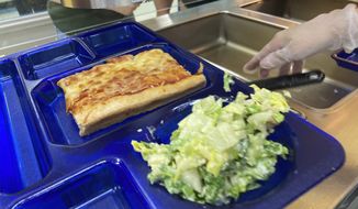 A student lunch of homemade pizza and caesar salad is placed on a tray at the Albert D. Lawton Intermediate School, in Essex Junction, Vt., Thursday, June 9, 2022. The pandemic-era federal aid that made school meals available for free to all public school students — regardless of family income levels — is ending, raising fears about the effects in the upcoming school year for families already struggling with rising food and fuel costs.  (AP Photo/Lisa Rathke)