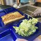 A student lunch of homemade pizza and caesar salad is placed on a tray at the Albert D. Lawton Intermediate School, in Essex Junction, Vt., Thursday, June 9, 2022. The pandemic-era federal aid that made school meals available for free to all public school students — regardless of family income levels — is ending, raising fears about the effects in the upcoming school year for families already struggling with rising food and fuel costs.  (AP Photo/Lisa Rathke)