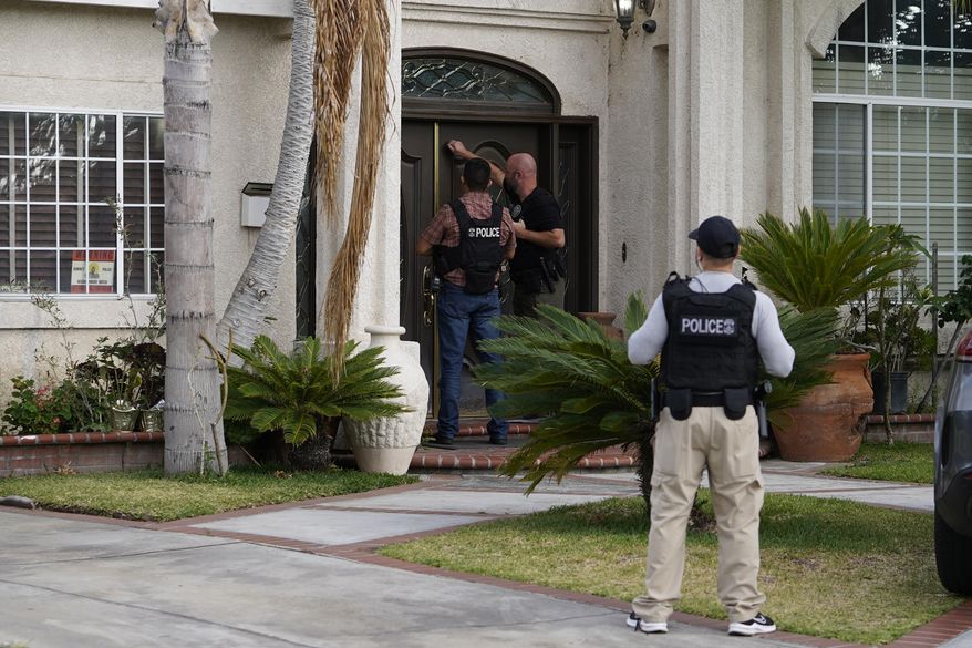 U.S. Immigration and Customs Enforcement agents knock at a residence after an arrest of an immigrant during an early morning raid in Duarte, Calif., Monday, June 6, 2022. This weekend, the Biden administration said it would suspend an order prioritizing the arrest and deportation of immigrants considered a threat to public safety and national security in order to comply with a ruling earlier in June 2022, from a Texas judge. Many otherwise law-abiding immigrants living here illegally will now be afraid to leave their homes out of concern they'll be detained. (AP Photo/Damian Dovarganes)