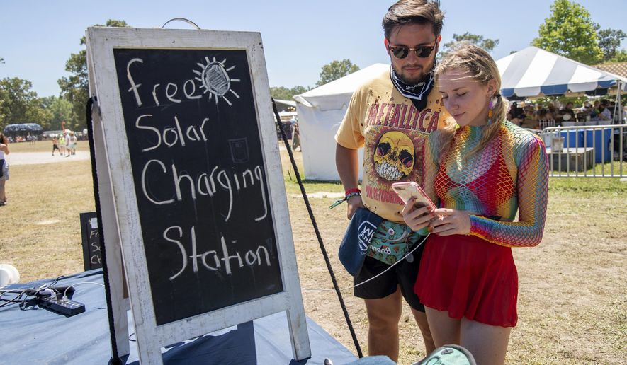 Festivalgoers use the free solar charging station at the Bonnaroo Music and Arts Festival on Saturday, June 18, 2022, in Manchester, Tenn. (Photo by Amy Harris/Invision/AP)