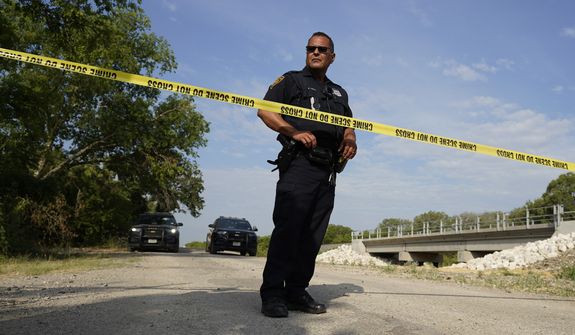 A San Antonio police officer protects the scene, Tuesday, June 28, 2022, in San Antonio, where officials say dozens of people have been found dead and multiple others were taken to hospitals with heat-related illnesses after a semitrailer containing suspected migrants was found. (AP Photo/Eric Gay)