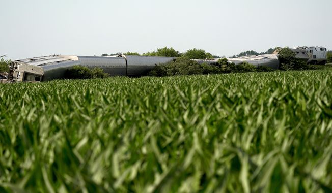 An Amtrak train which derailed after striking a dump truck is seen beyond a corn field Monday, June 27, 2022, near Mendon, Mo. (AP Photo/Charlie Riedel)