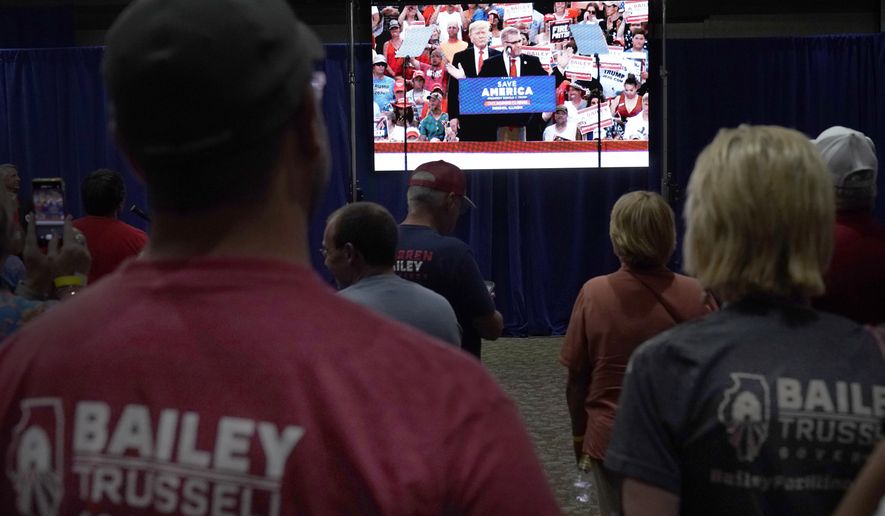 Supporters of Republican gubernatorial primary candidate Illinois state Sen. Darren Bailey watch a video Tuesday, June 28, 2022, in Effingham, Ill., at Bailey election headquarters, of former President Trump recently campaigning for Bailey. (AP Photo/Charles Rex Arbogast)