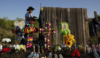 Roberto Marquez of Dallas secures a cross to a make-shift memorial at the site where officials found dozens of people dead in an abandoned semitrailer containing suspected migrants, Wednesday, June 29, 2022, in San Antonio. (AP Photo/Eric Gay)