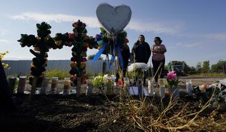 In this file photo, mourners pay their respects at a makeshift memorial at the site where officials found dozens of people dead in an abandoned semitrailer containing suspected migrants, Wednesday, June 29, 2022, in San Antonio. The man accused of orchestrating the smuggling journey that cost 53 migrants their lives was already under &quot;active investigation&quot; by ICE agents in Texas, according to court documents. (AP Photo/Eric Gay)  **FILE**