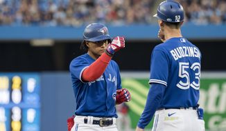 Toronto Blue Jays&#39; Santiago Espinal (5) celebrates with first base coach Mark Budzinski after hitting a single against the Boston Red Sox during the second inning of a baseball game Wednesday, June 29, 2022, in Toronto. (Christopher Katsarov/The Canadian Press via AP)