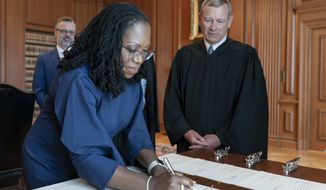 In this image provided by the Collection of the Supreme Court of the United States, Supreme Court Justice Ketanji Brown Jackson signs the Oaths of Office at the Supreme Court in Washington, Thursday, June 30, 2022, as Chief Justice of the United States John Roberts watches. (Fred Schilling/Collection of the Supreme Court of the United States via AP)