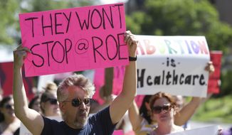 A man holds a sign as community members walk around Vander Veer Park during a march following the Supreme Court decision to overturn Roe v. Wade, June 26, 2022, in Davenport, Iowa. Democrats and their aligned groups raised more than $80 million in the week after the Supreme Court stripped away a woman’s constitutional right to have an abortion. The flood of cash offers one of the first tangible signs of how the ruling may energize voters. (Nikos Frazier/Quad City Times via AP)