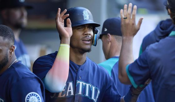 Seattle Mariners&#39; Julio Rodriguez is greeted in the dugout after scoring on a sacrifice hit by Abraham Toro against the Oakland Athletics during first inning of a baseball game, Thursday, June 30, 2022, in Seattle. (AP Photo/John Froschauer)