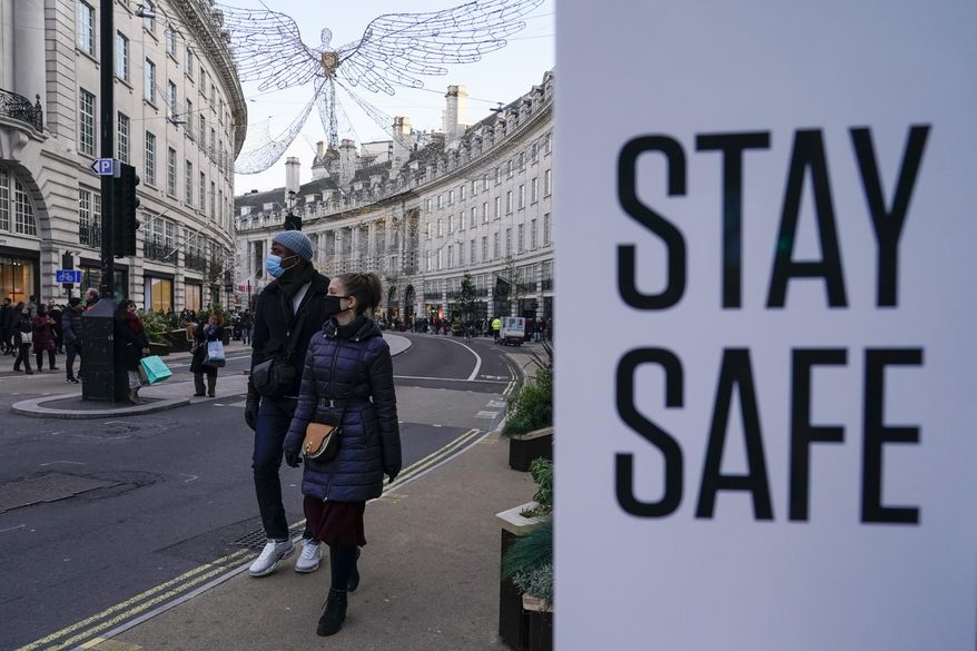 People wear face masks as they walk, in Regent Street, in London, Sunday, Nov. 28, 2021 (AP Photo/Alberto Pezzali, File)