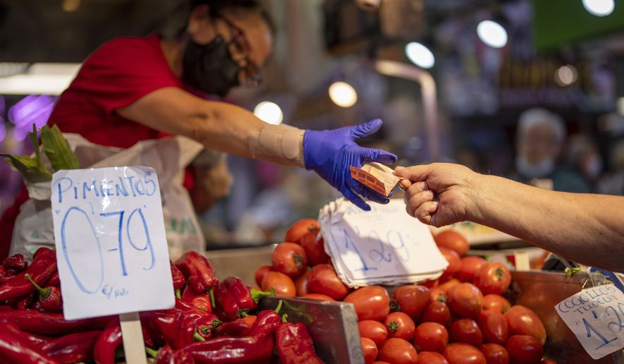 A customer pays for vegetables at the Maravillas market in Madrid, on May 12, 2022. Inflation figures for Europe will be released Friday, July 1, 2022, as Russia&#39;s war in Ukraine has worsened the worldwide surge in consumer prices. For months, inflation in the 19 countries that use the euro has risen at the fastest pace since record-keeping for the currency began. (AP Photo/Manu Fernandez, File)