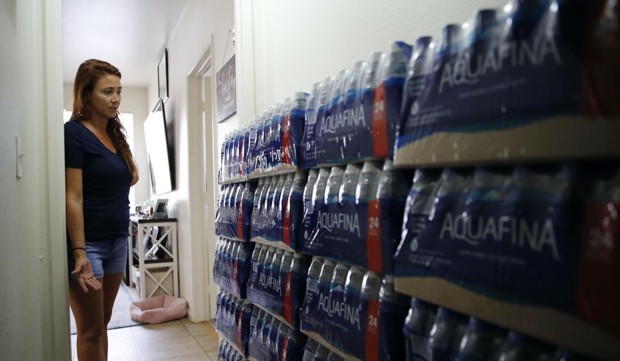 Lauren Wright, a Navy spouse whose family was sickened by jet fuel in their tap water, shows her supply of bottled water at her home in Honolulu, Friday, July 1, 2022. A Navy investigation says shoddy management and human error caused fuel to leak into Pearl Harbor&#39;s tap water last year. The leak poisoned thousands of people and forced military families to evacuate their homes for hotels. (AP Photo/Caleb Jones)
