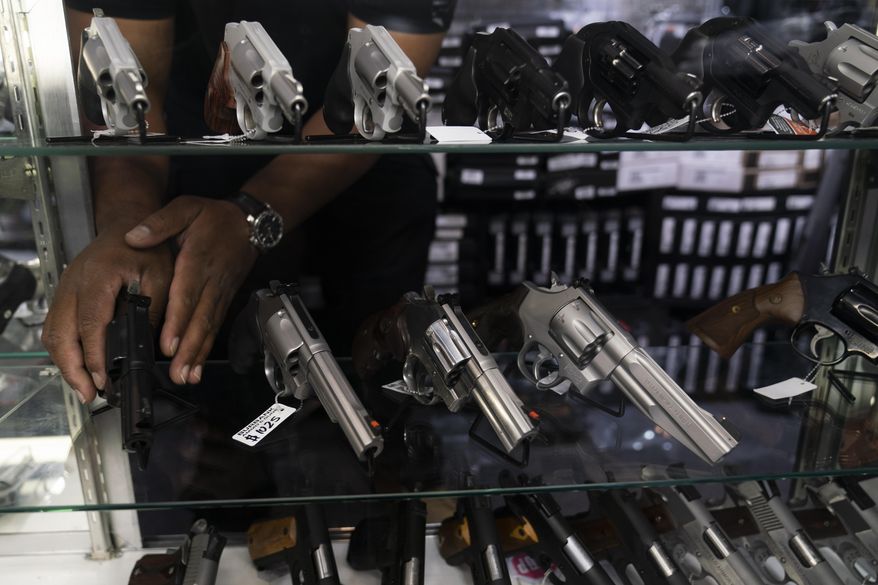 Sales associate Elsworth Andrews arranges guns on display at Burbank Ammo &amp;amp; Guns in Burbank, Calif., Thursday, June 23, 2022. The Supreme Court has ruled that Americans have a right to carry firearms in public for self-defense, a major expansion of gun rights. The court struck down a New York gun law in a ruling expected to directly impact half a dozen other populous states. (AP Photo/Jae C. Hong) ** FILE **