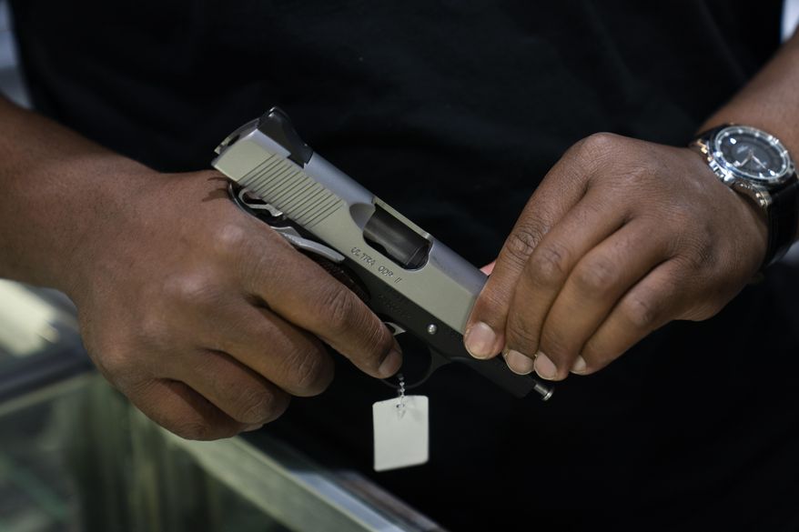 Sales associate Elsworth Andrews shows a handgun to a customer at Burbank Ammo & Guns in Burbank, Calif., Thursday, June 23, 2022. The Supreme Court has ruled that Americans have a right to carry firearms in public for self-defense, a major expansion of gun rights. The court struck down a New York gun law in a ruling expected to directly impact half a dozen other populous states. (AP Photo/Jae C. Hong) **FILE**