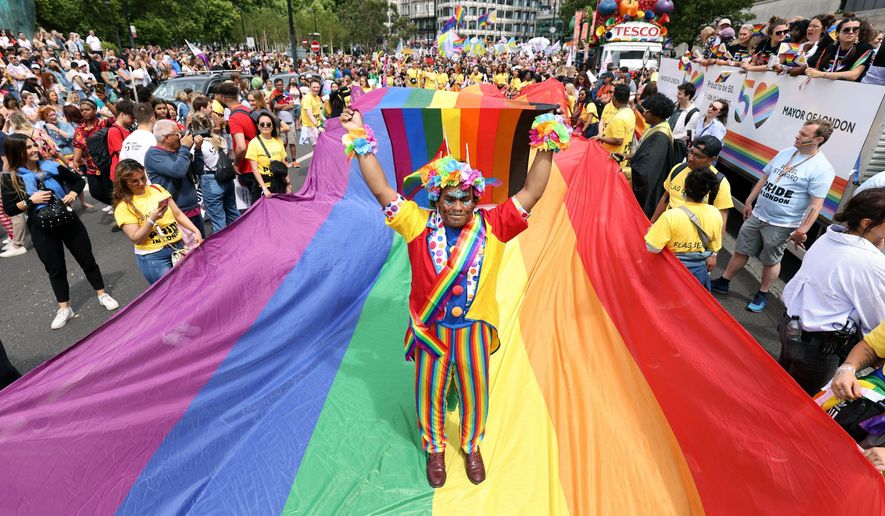 Mohammed Nazir from London, poses on a giant rainbow flag, during the Pride in London parade, in London, Saturday, July 2, 2022, marking the 50th Anniversary of the Pride movement in the UK. (James Manning/PA via AP)