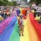 Mohammed Nazir from London, poses on a giant rainbow flag, during the Pride in London parade, in London, Saturday, July 2, 2022, marking the 50th Anniversary of the Pride movement in the UK. (James Manning/PA via AP)