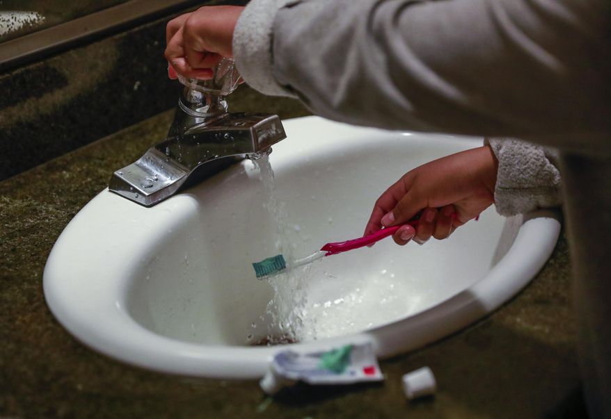 A child rinses a toothbrush at a shelter in San Francisco, Calif., June 18, 2019. Tap water is subject to a rash of government standards but people in many communities across the U.S. remain exposed to unhealthy drinking water. A Supreme Court decision on EPA regulation of carbon emissions from power plants this past week could make it harder to expand federal regulation in other areas. (Gabrielle Lurie/San Francisco Chronicle via AP, File)