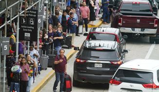 Travelers are seen outside of Terminal D at George Bush Intercontinental Airport, Friday, July 1, 2022, in Houston. The July Fourth holiday weekend is off to a booming start with airport crowds crushing the numbers seen in 2019, before the pandemic. (AP Photo/Julio Cortez)