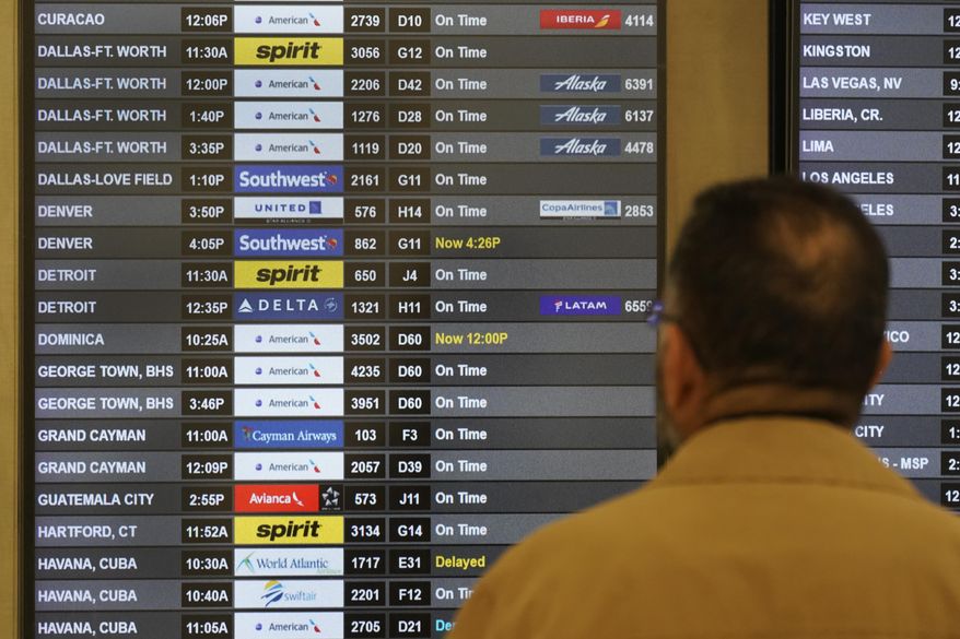 A traveler looks at the flight board at Miami International Airport, Friday, July 1, 2022, in Miami. The July Fourth holiday weekend is off to a booming start with airport crowds crushing the numbers seen in 2019, before the pandemic.  (AP Photo/Wilfredo Lee)