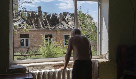 Victor Rosenberg, 81, looks out of a broken window in his home destroyed by the Russian rocket attack in the city centre of Bakhmut, Donetsk region, Ukraine, Friday, July 1, 2022. (AP Photo/Efrem Lukatsky)