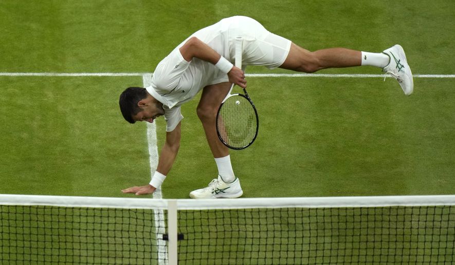 Serbia&#39;s Novak Djokovic touches the grass as he celebrates defeating Tim van Rijthoven of the Netherlands during a men&#39;s fourth round singles match on day seven of the Wimbledon tennis championships in London, Sunday, July 3, 2022.(AP Photo/Alastair Grant))