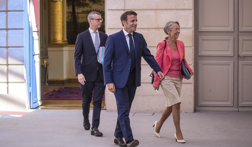 French President Emmanuel Macron, center, and Prime Minister Elisabeth Borne, right, arrive to attend the first cabinet meeting with new ministers at the Elysee Palace in Paris, Monday, July 4, 2022. French President Emmanuel Macron rearranged his Cabinet on Monday in an attempt to adjust to a new political reality following legislative elections in which his centrist alliance failed to win a majority in the parliament. (Christophe Petit Tesson, Pool via AP)
