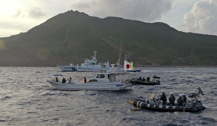 Japanese Coast Guard vessel and boats, rear and right, sail alongside a Japanese activists&#39; fishing boat, center with a flag, near a group of disputed islands called Diaoyu by China and Senkaku by Japan, early Sunday, Aug. 18, 2013. Japan protested to Beijing after spotting Chinese and Russian warships just outside of Japanese territorial waters around the disputed East China Sea islands earlier Monday, July 4, 2022, prompting criticisms from China. (AP Photo/Emily Wang) **FILE**