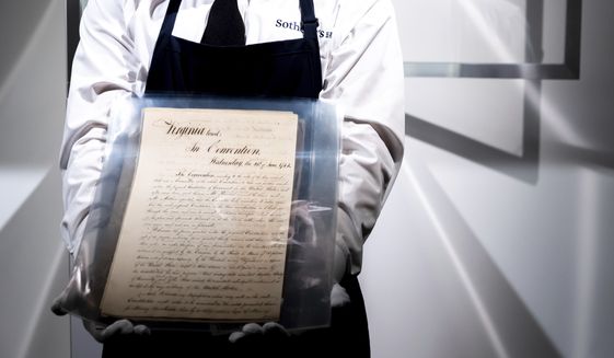 A Sotheby&#39;s New York employee holds Virginia&#39;s Official Ratification of the United States Constitution, a defining document of early American government and precursor to the U.S. Bill of Rights, Tuesday, July 5, 2022, in New York. The document will go to auction on July 21, 2022 and is expected to sell for $3-5 millions. (AP Photo/Julia Nikhinson)