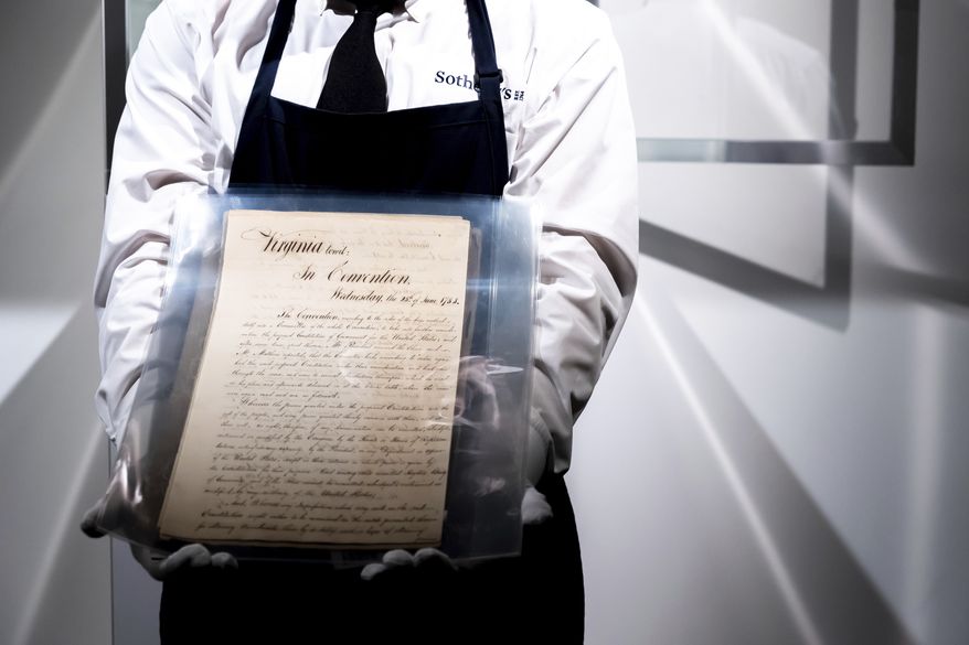A Sotheby&#39;s New York employee holds Virginia&#39;s Official Ratification of the United States Constitution, a defining document of early American government and precursor to the U.S. Bill of Rights, Tuesday, July 5, 2022, in New York. The document will go to auction on July 21, 2022 and is expected to sell for $3-5 millions. (AP Photo/Julia Nikhinson)