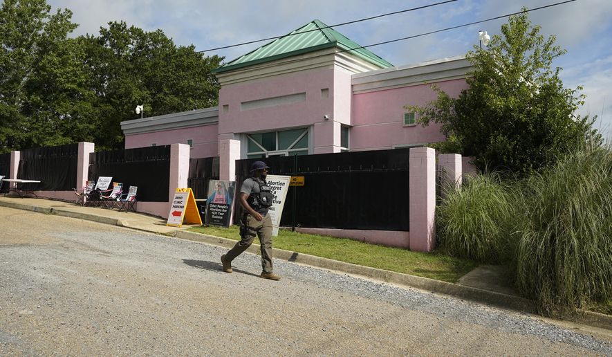 A security officer walks past the front of the Jackson Women&#39;s Health Organization clinic in Jackson, Miss., Sunday, July 3, 2022. The medical facility was open for three hours before anti-abortion protesters arrived. The clinic is the only facility that performs abortions in the state. On June 24, the U.S. Supreme Court overturned Roe v. Wade, ending constitutional protections for abortion. However, a Mississippi judge has set a hearing for Tuesday, in a lawsuit by the state&#39;s only abortion clinic that seeks to block a law that would ban most abortions. (AP Photo/Rogelio V. Solis)