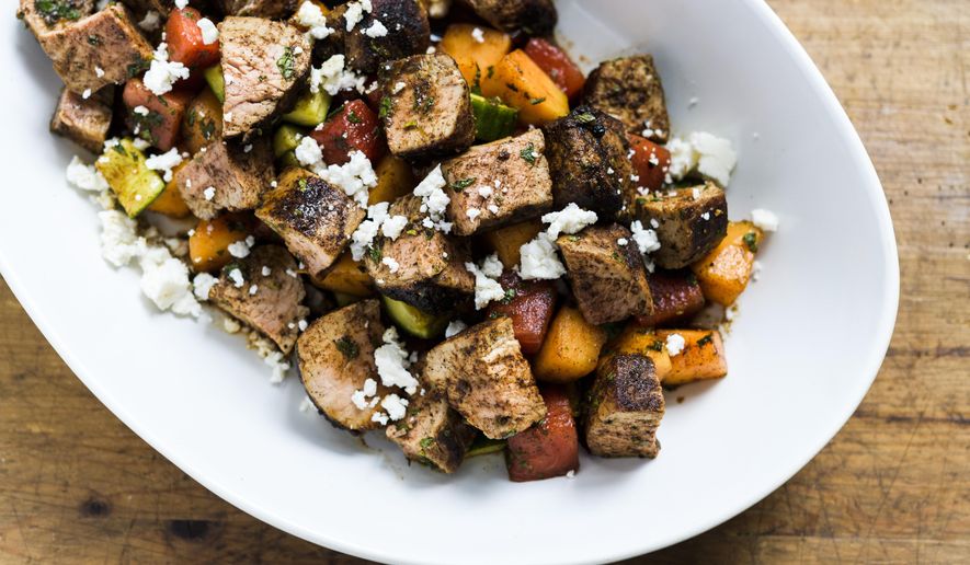 This image released by Milk Street shows a recipe for Chili-rubbed Pork with Cucumber-Melon Salad. (Milk Street via AP)