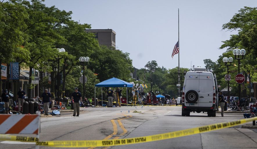 A flag hangs at half staff as members of the FBI&#39;s Evidence Response Team Unit investigate in downtown Highland Park, Ill., the day after a deadly mass shooting on Tuesday, July 5, 2022.   Police say the gunman who attacked an Independence Day parade in suburban Chicago fired more than 70 rounds with an AR-15-style gun.   (Ashlee Rezin /Chicago Sun-Times via AP)