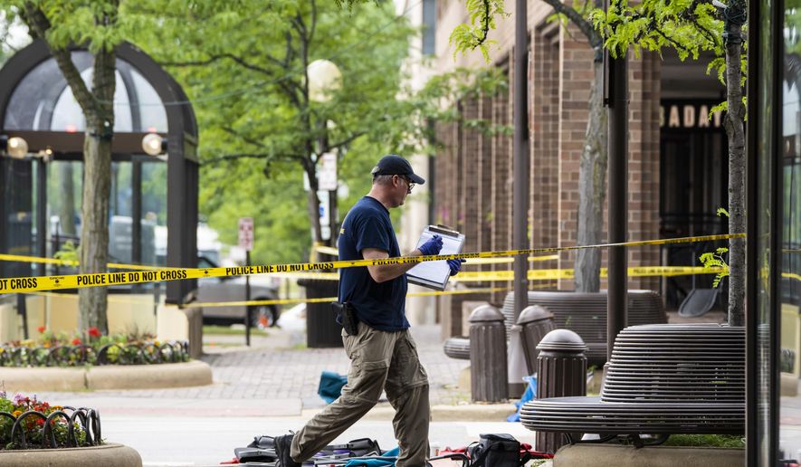 Members of the FBI's Evidence Response Team Unit investigate on Central Avenue near Green Bay Road in downtown Highland Park, Ill., less than 24 hours after a gunman killed several people and wounded dozens more by firing a high-powered rifle from a rooftop onto a crowd attending Highland Park's Fourth of July parade, Tuesday morning, July 5, 2022. (Ashlee Rezin/Chicago Sun-Times via AP)
